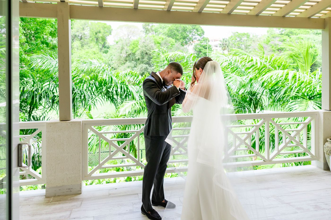 Newlyweds share first look moment under outdoor pavilion surrounded by lush tropical greenery.