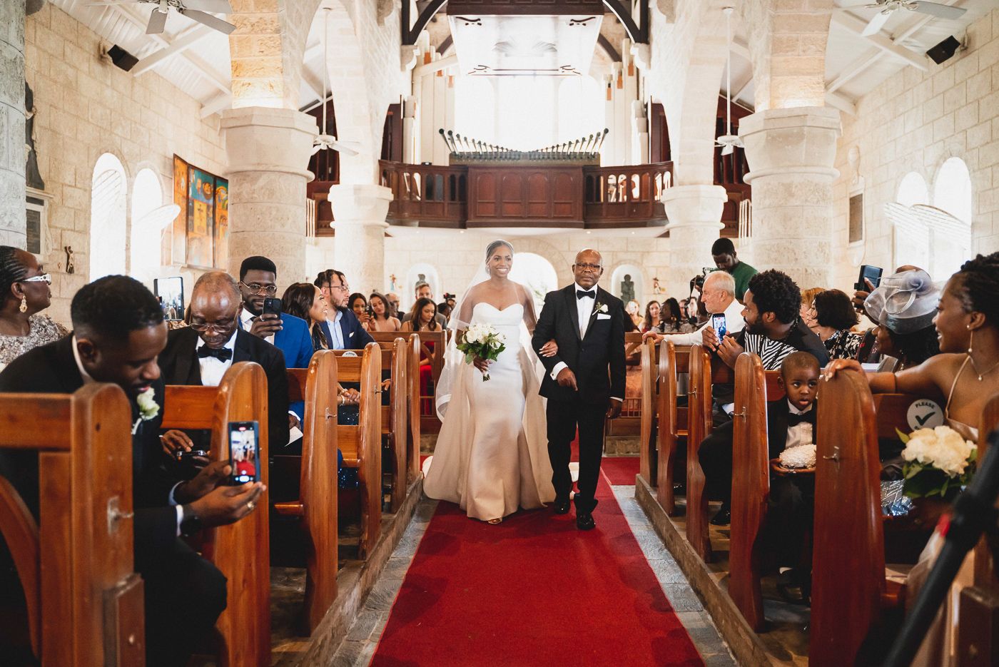 Wedding ceremony in historic church with vaulted ceilings and red carpet aisle.