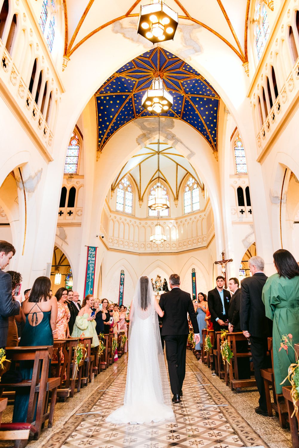 Wedding ceremony in a stunning Gothic cathedral with blue and gold vaulted ceiling and ornate architecture.