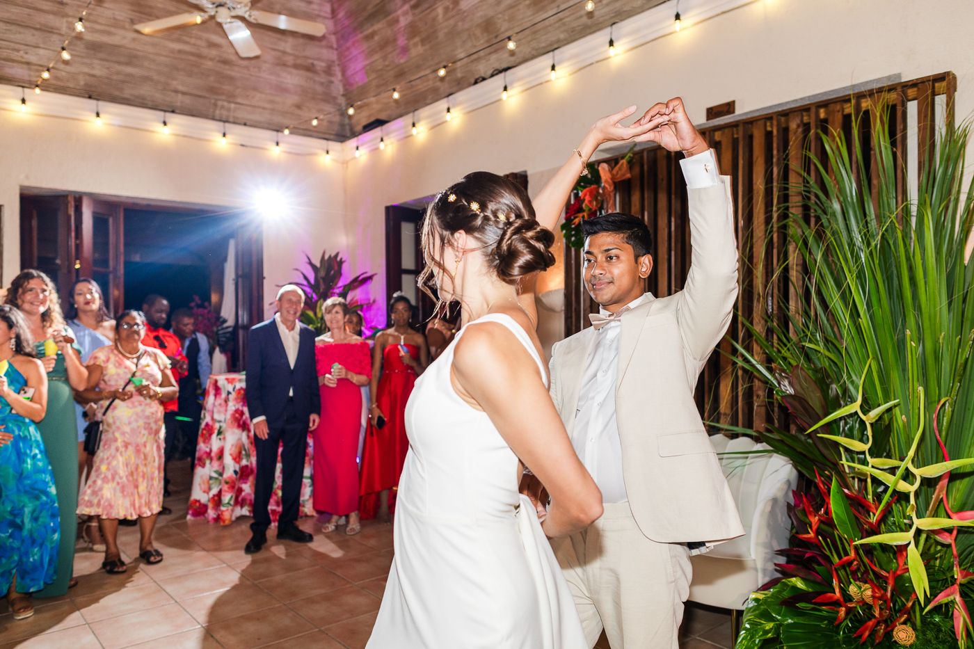 A couple shares their first dance at a wedding reception decorated with string lights.