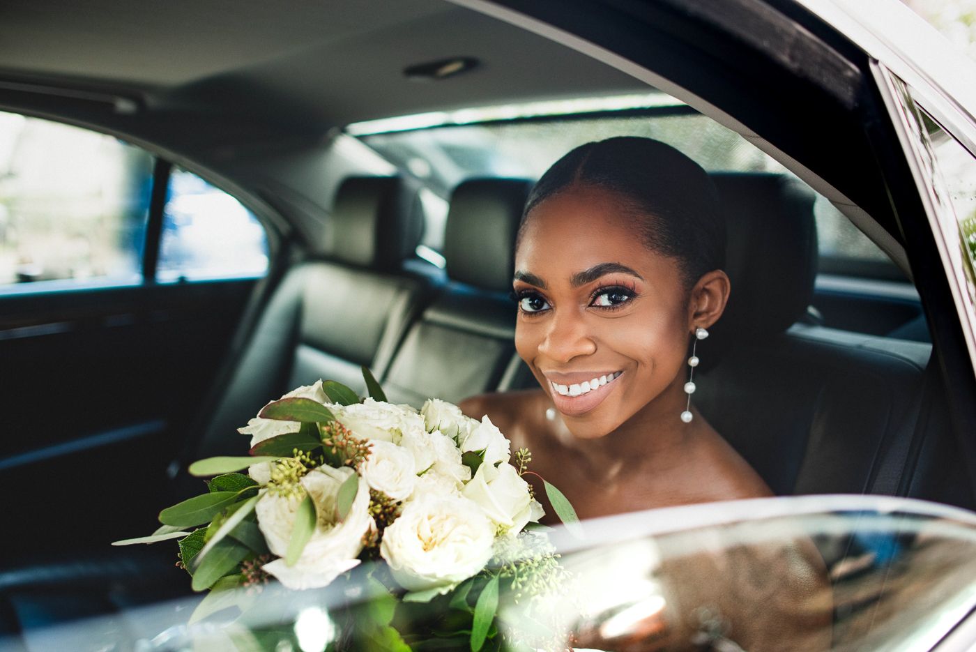 Elegant wedding bouquet of white roses sits in luxury car with leather interior.
