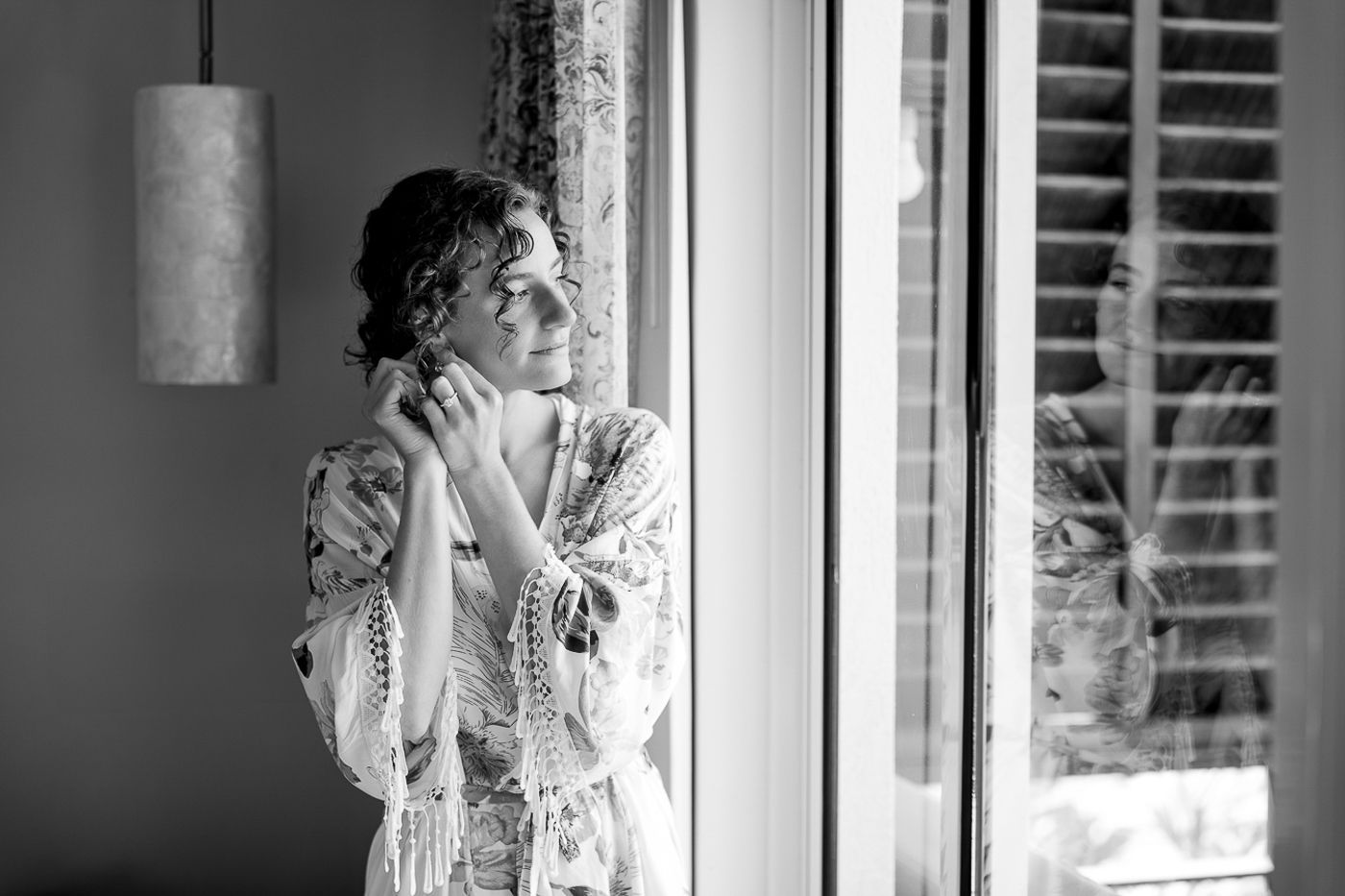 Getting ready moments captured through window light in black and white.