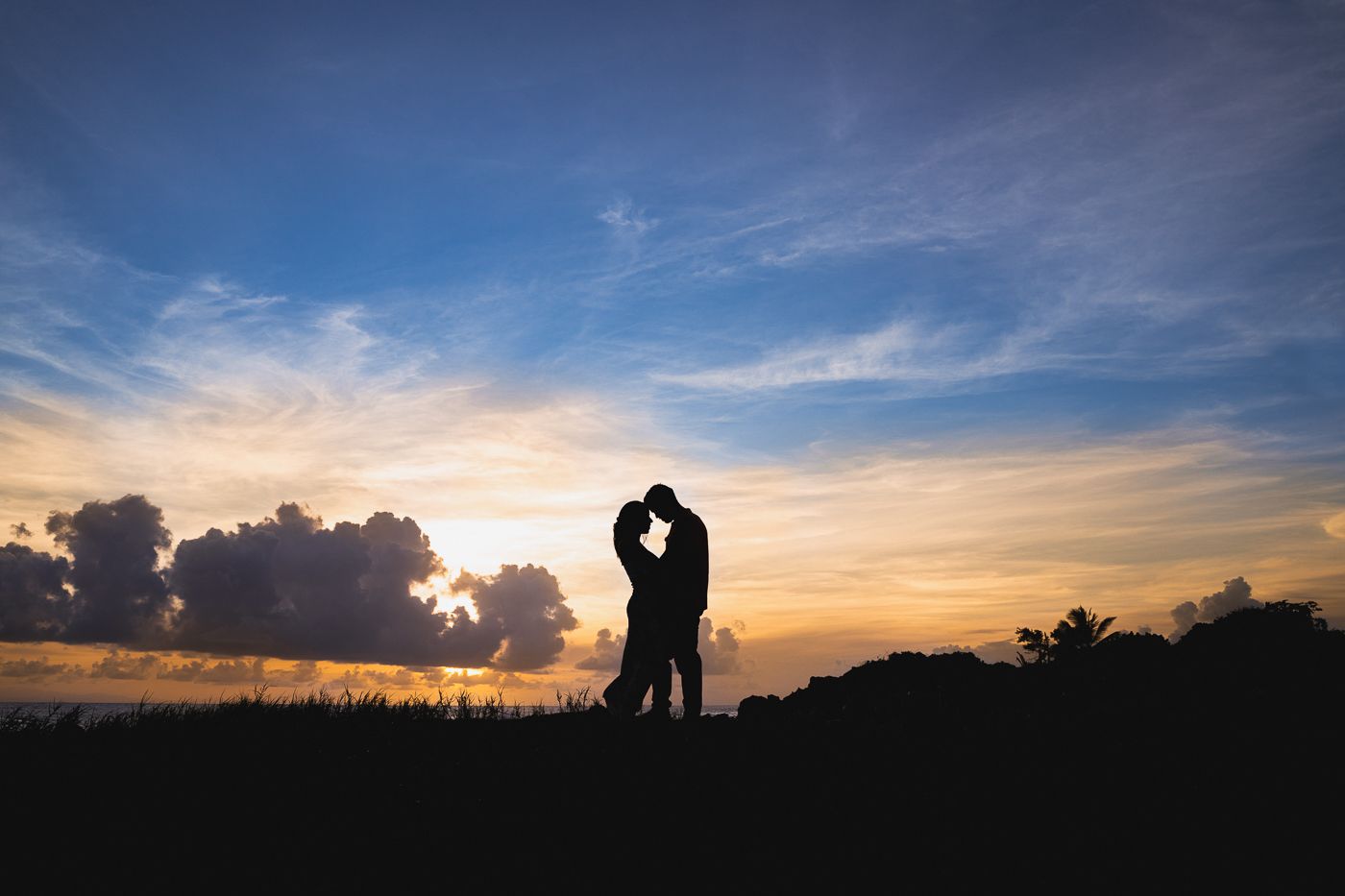 Romantic sunset silhouettes of wedding couple against dramatic sky.