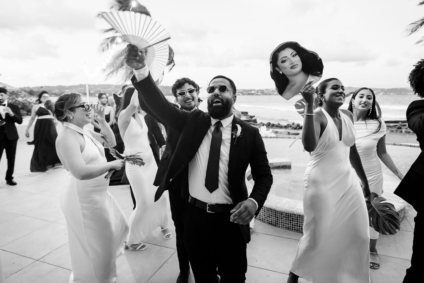 Wedding guests dancing and celebrating with arms raised at indoor reception.