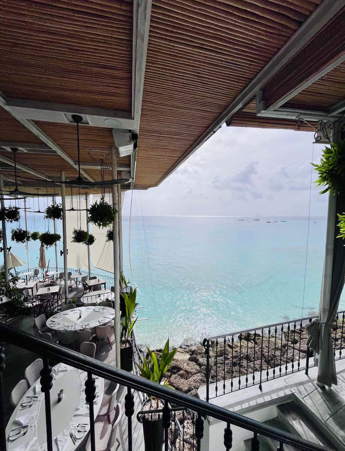 Elegant dining space with wood ceiling and glass walls offering panoramic seaside views. QP bistro wedding venue in barbados