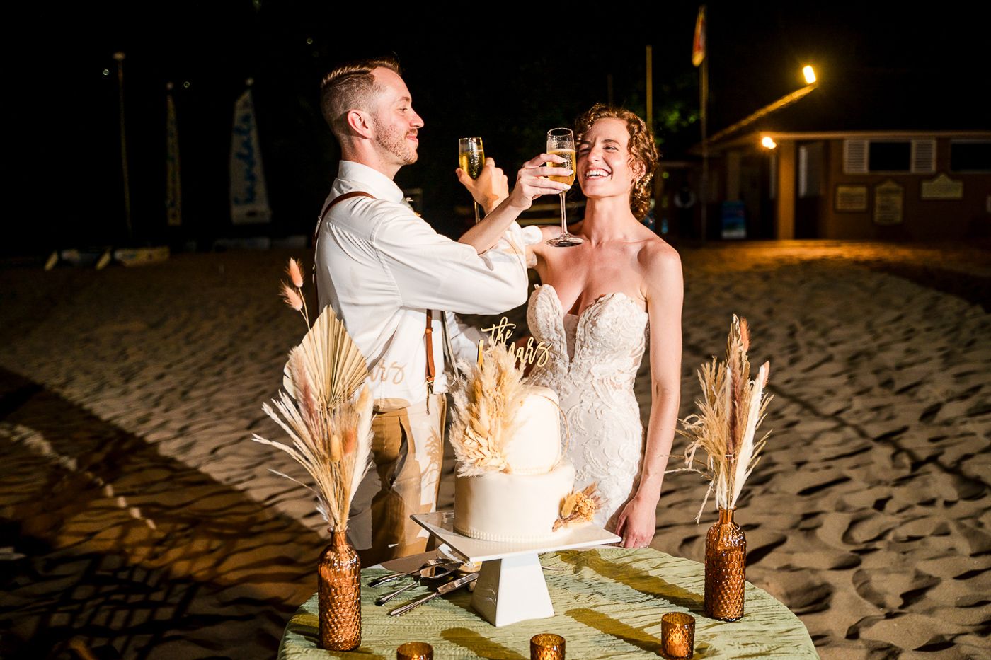 Newlyweds share a romantic moment at their candlelit beach reception table.