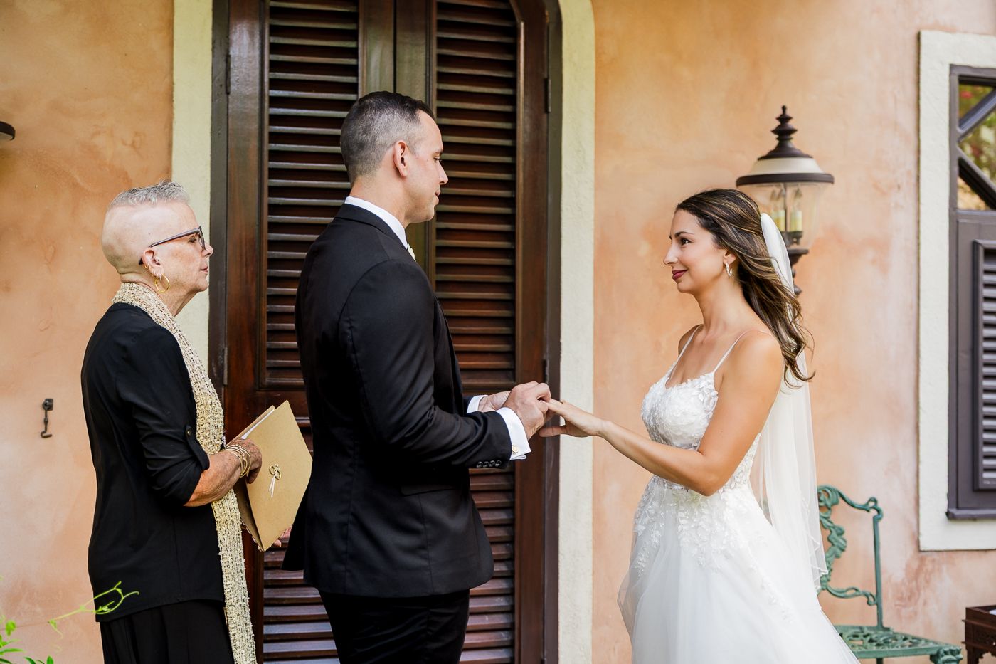Bride and groom exchanging vows outdoors with officiant at a tropical wedding ceremony.