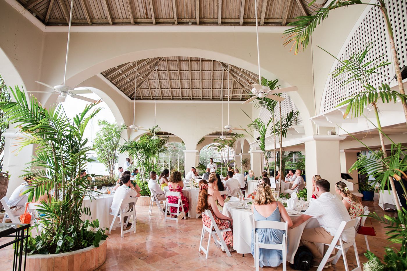 Elegant tropical wedding reception venue with high ceilings, white columns and palm trees.