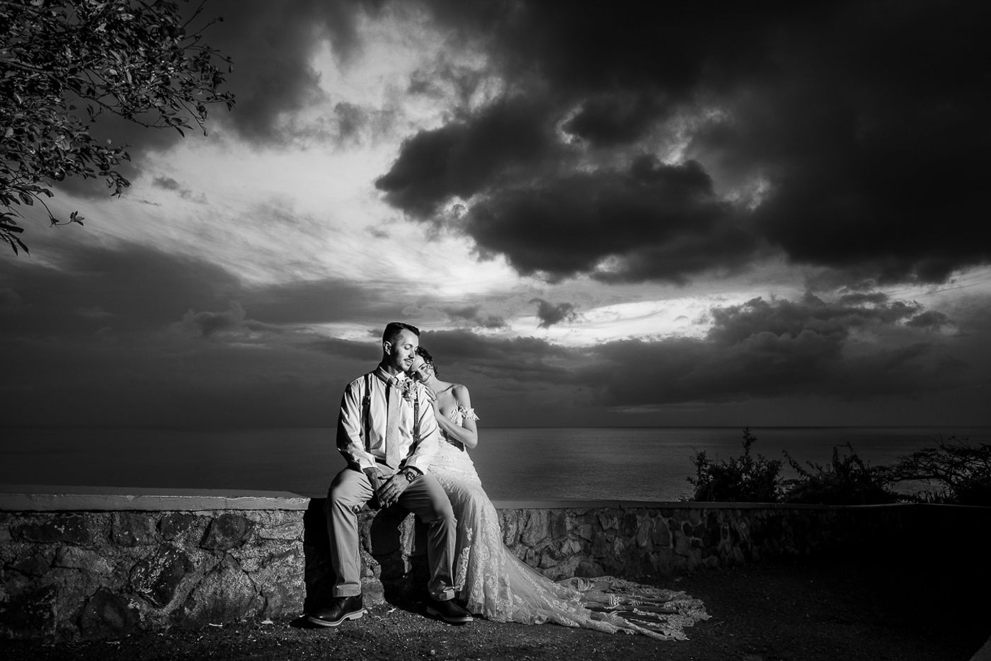 Dramatic black and white beach wedding portraits with stormy skies and ocean backdrop.