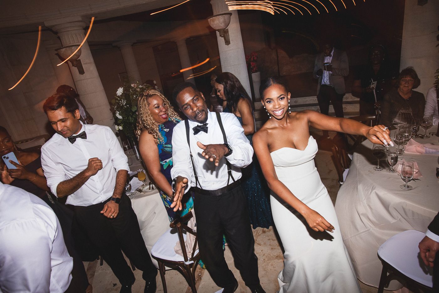 Wedding guests dancing and celebrating on the dance floor at an evening reception.