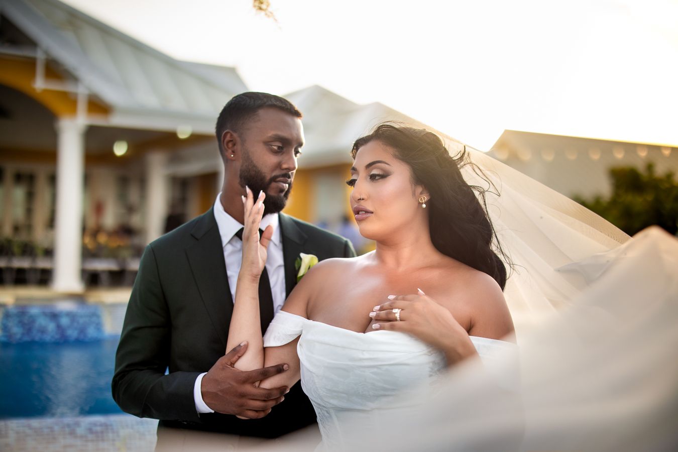 Couple shares romantic moments by a pool during their tropical destination wedding photoshoot.