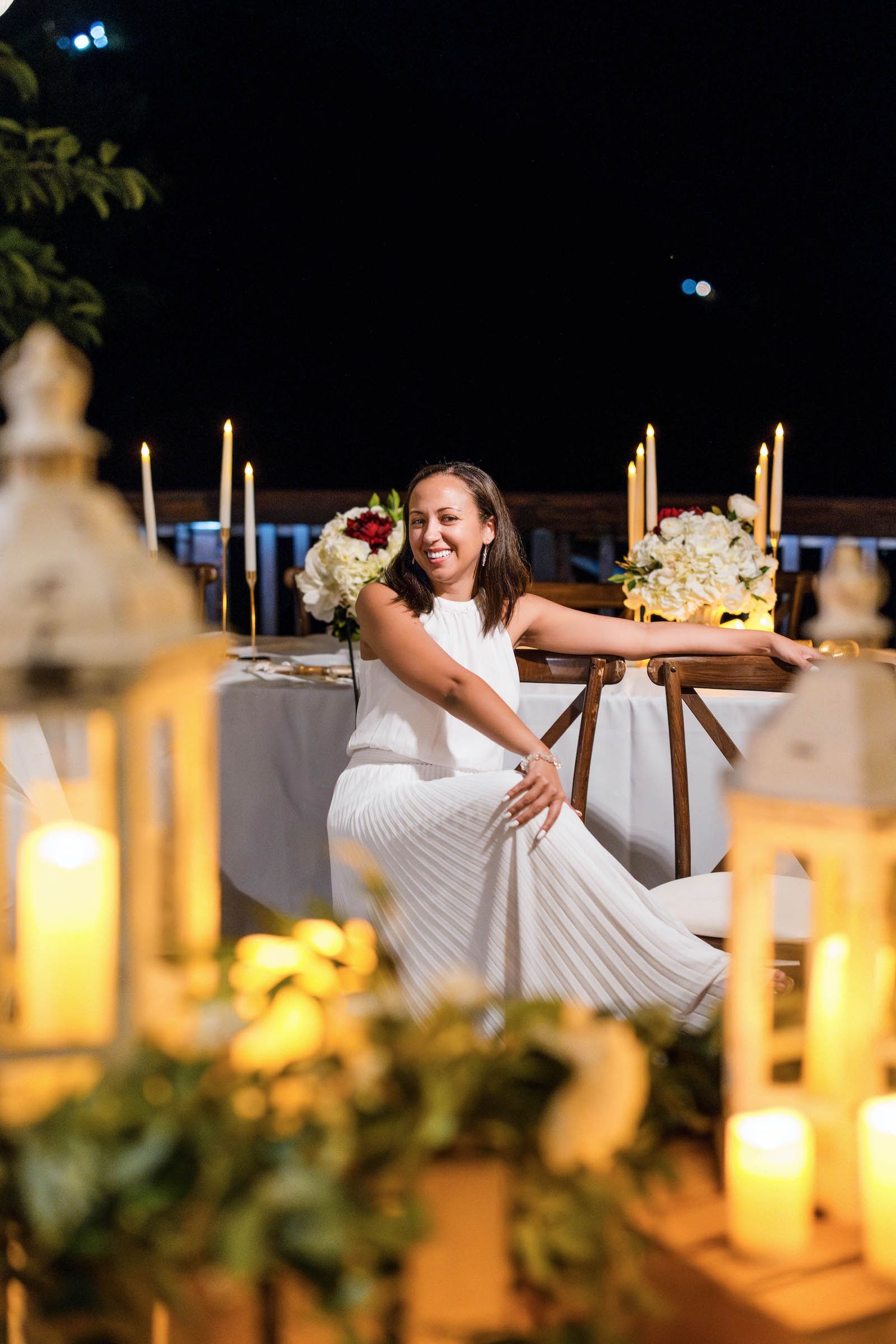 Wedding reception setup with glowing lanterns and table decorations at night.