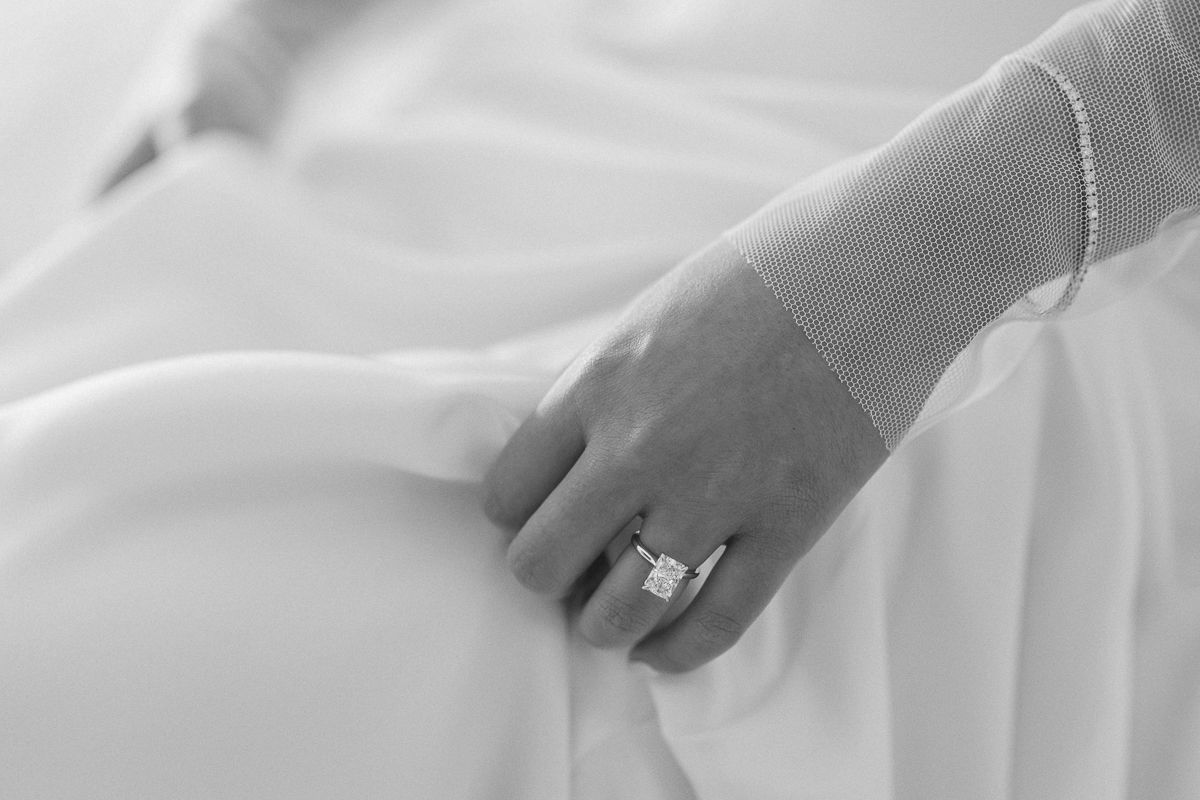 Close-up of white wedding dress details showing intricate lace and beading patterns.