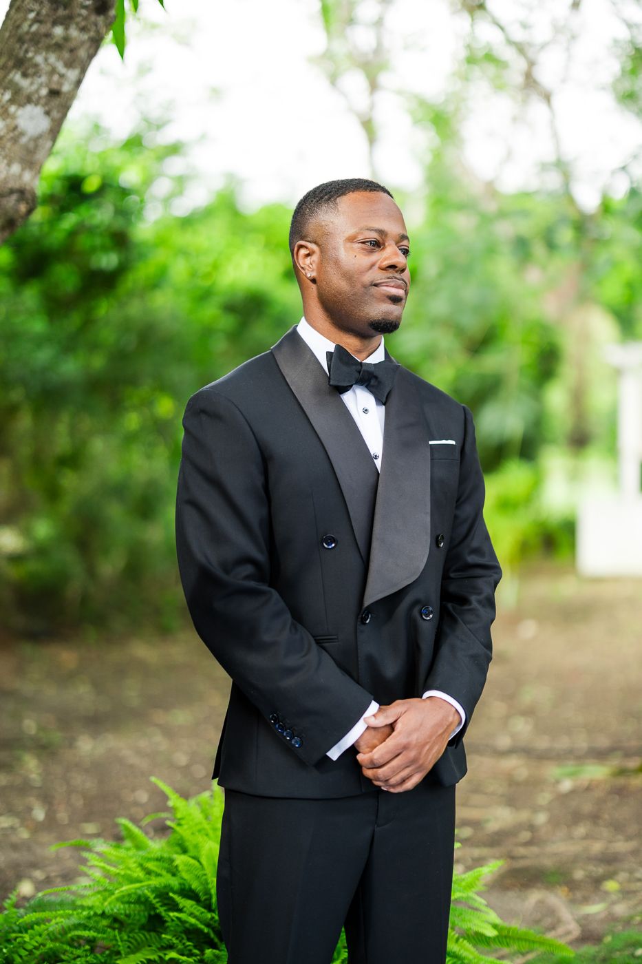 Formal wedding attire captured in an elegant outdoor garden setting with lush greenery.