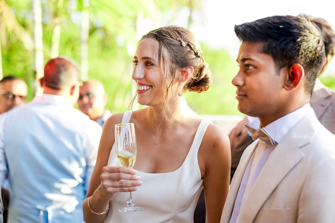 Wedding guests celebrate with drinks at an outdoor reception during golden hour.