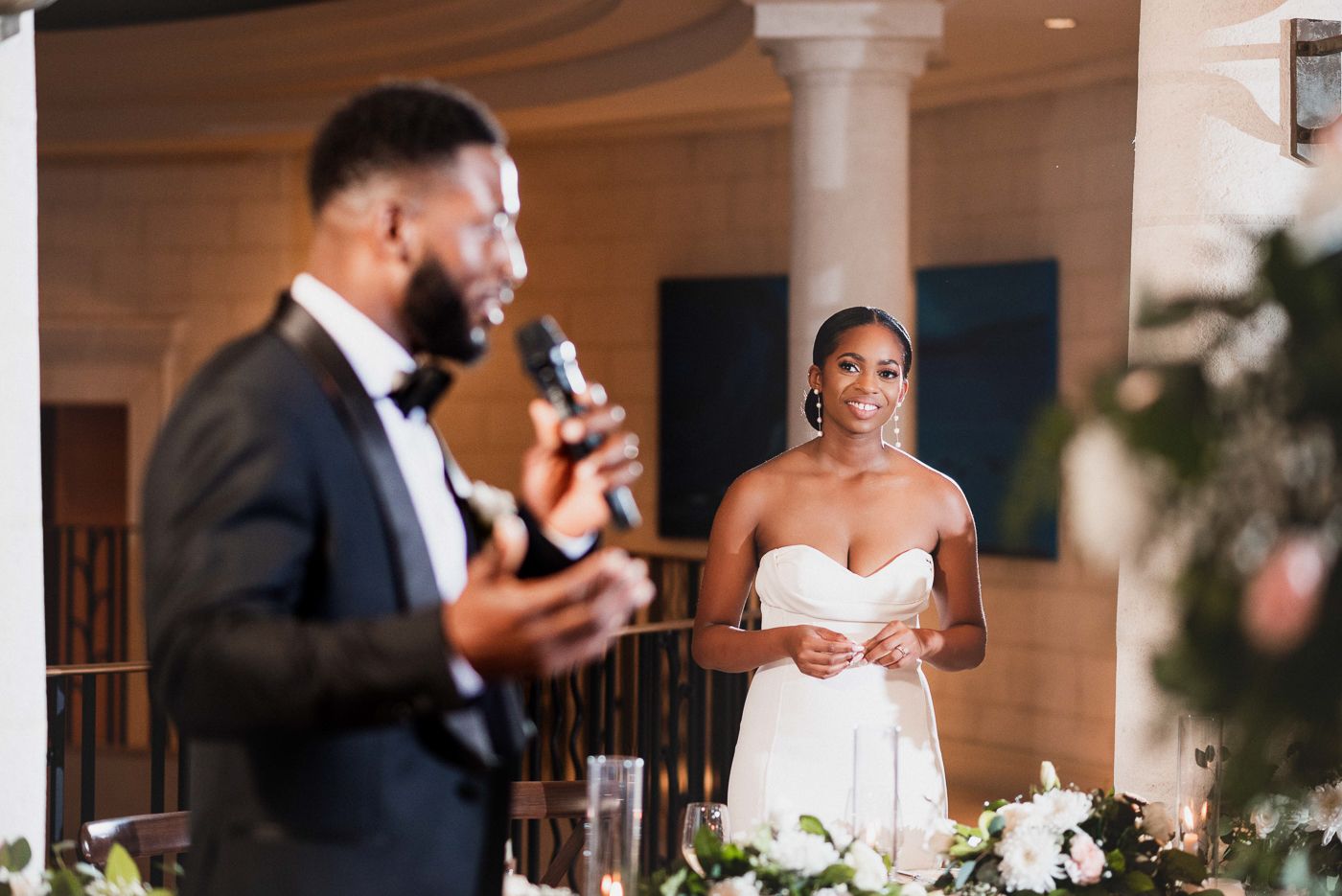 Wedding guests giving emotional toasts during reception speeches in an elegant ballroom setting.