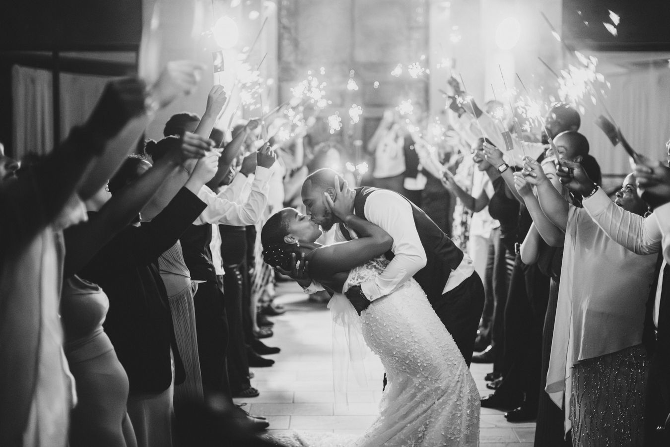 Sparkler exit tunnel with couple sharing romantic moment in black and white.