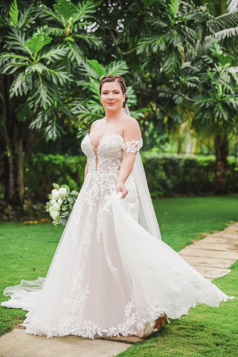 Elegant wedding dress with lace details in a lush tropical garden setting.