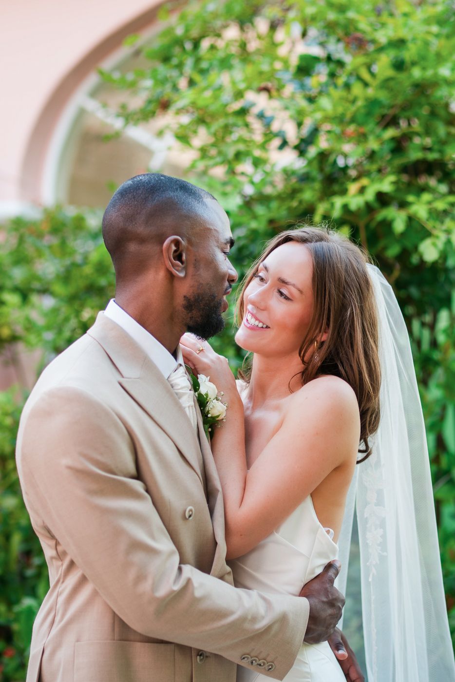 Intimate wedding portrait of couple sharing tender moment against garden archway.