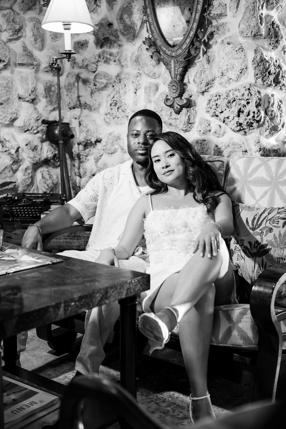 A couple relaxes in a vintage-styled room with stone walls and antique decorations.