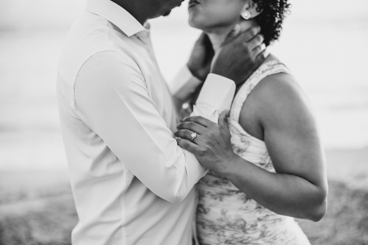 Black and white wedding photos show romantic moments between a couple on a beach at sunset.