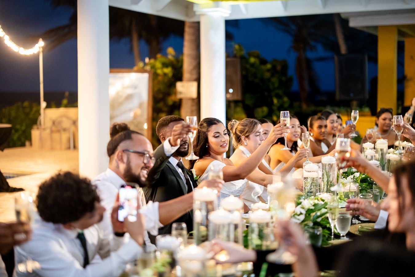 Evening wedding reception with guests celebrating under ambient lighting.