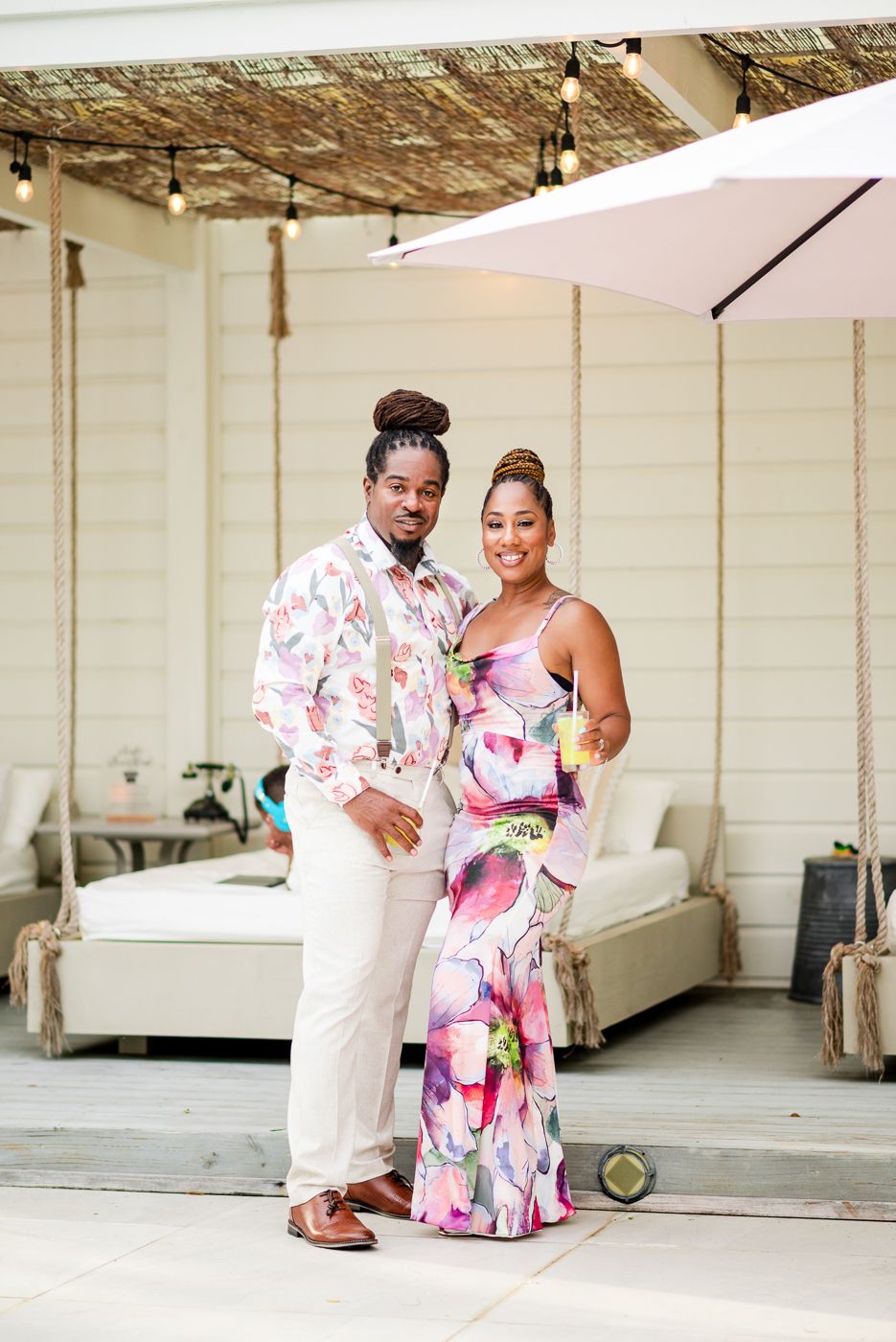 Couple in coordinating floral outfits pose together at an elegant outdoor event.