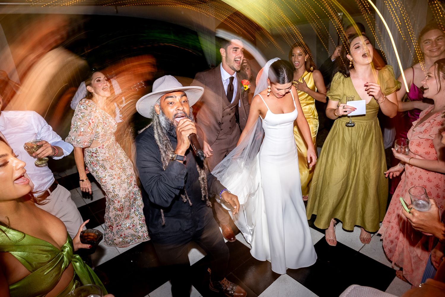 Guests dance and celebrate together on a crowded dance floor at an evening wedding reception party.