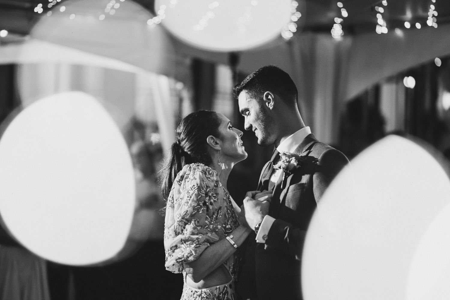 A romantic black and white dance moment with soft bokeh lights in an elegant indoor venue.