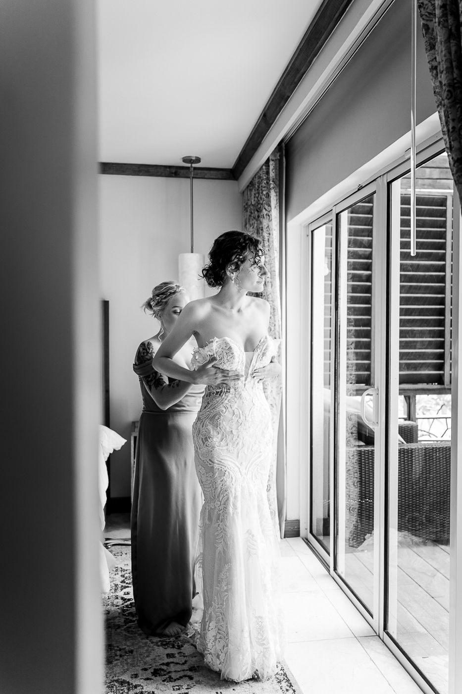 Black and white photos showing someone helping with dress preparations by a window.