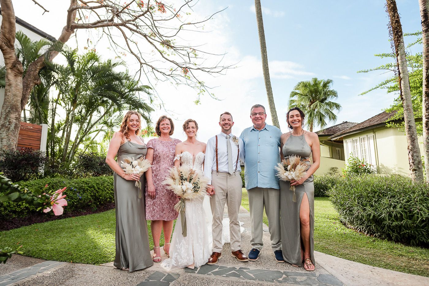Wedding party photo with bridesmaids in gray dresses and groomsmen in casual beach attire.