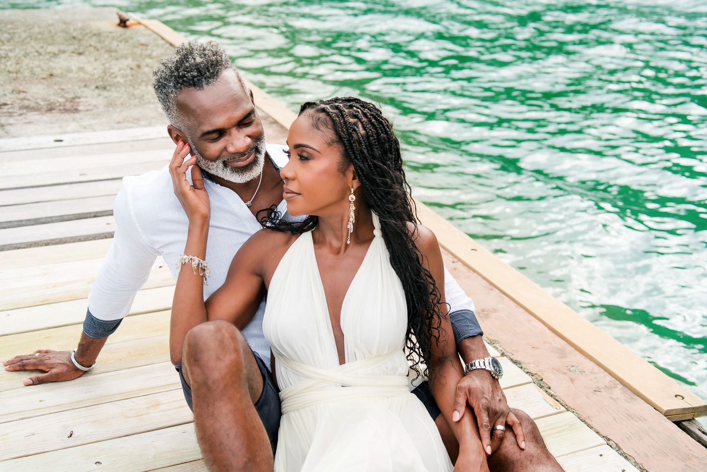 Intimate couple portraits captured on wooden deck beside turquoise waters.