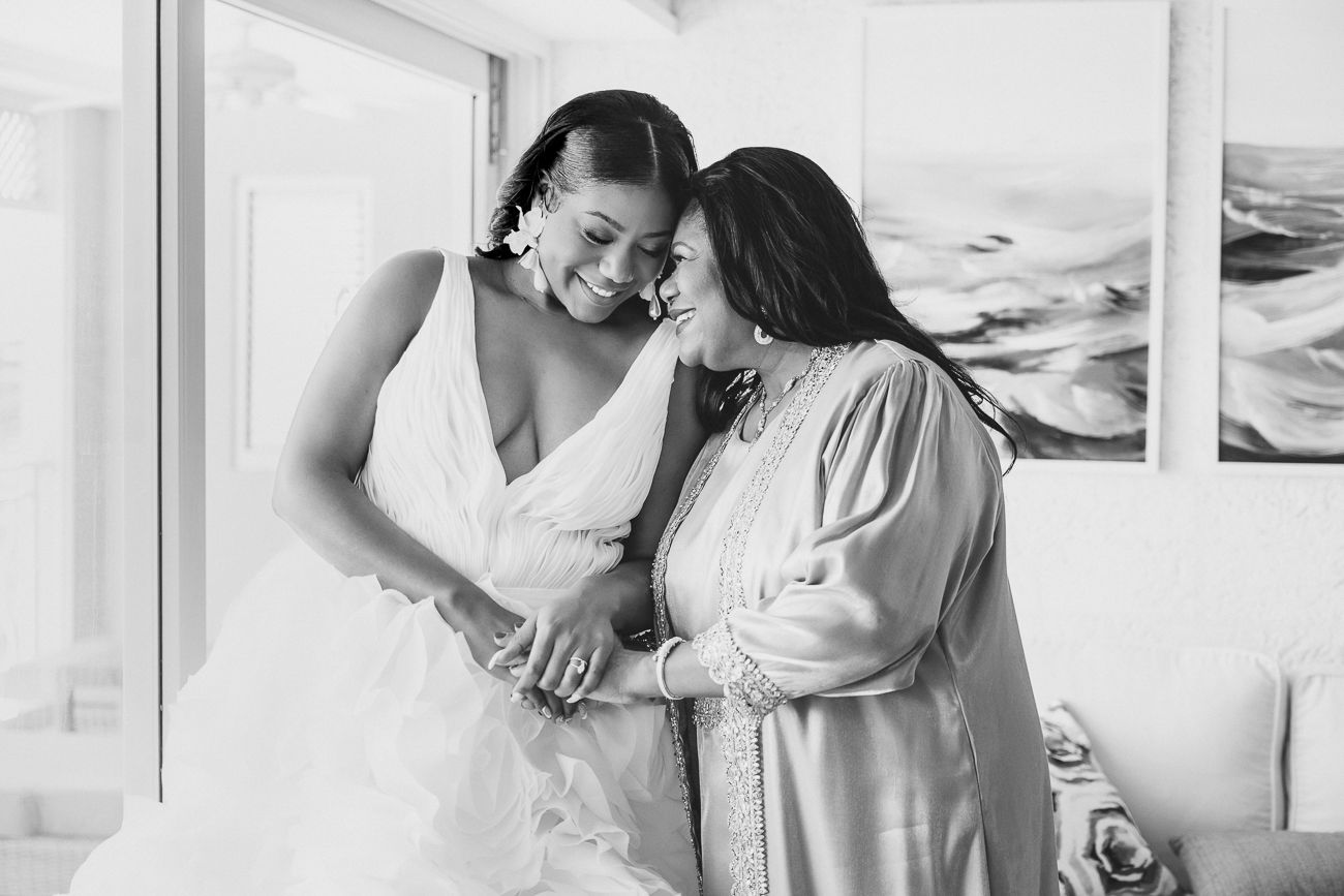 Black and white photo of a bride in a white gown sharing a tender moment with her mother on her wedding day.