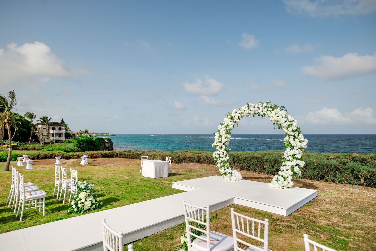 beachside wedding ceremony setup with white floral arches and chairs overlooking the ocean. the crane resort barbados wedding venues