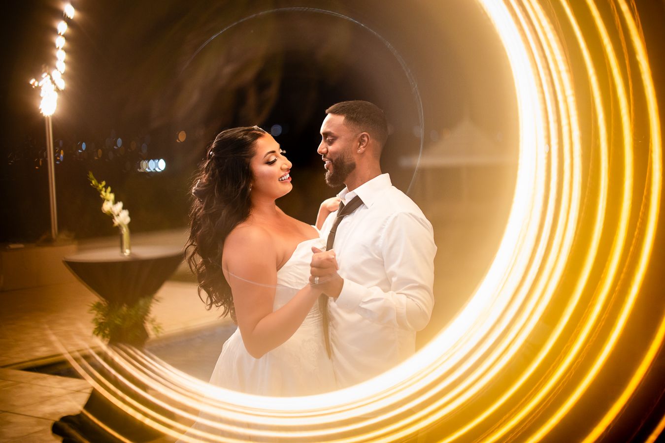 Couple dancing in front of circular light trail creating romantic evening portrait.