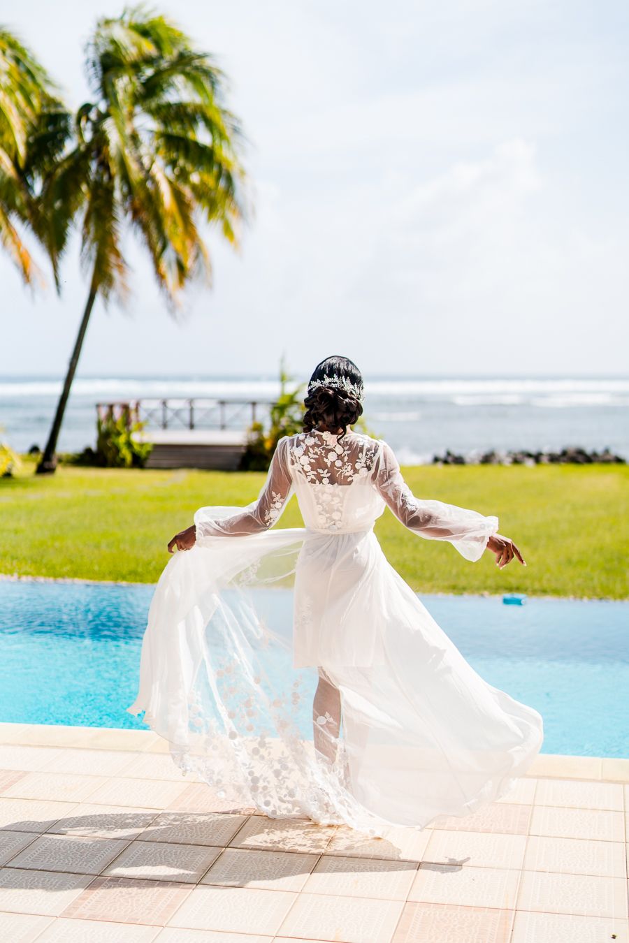 Ethereal bridal portrait showing flowing dress movement by infinity pool with ocean view.