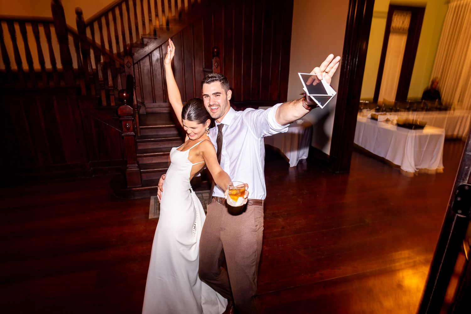 Wedding guests dancing together at a dimly lit reception party venue.