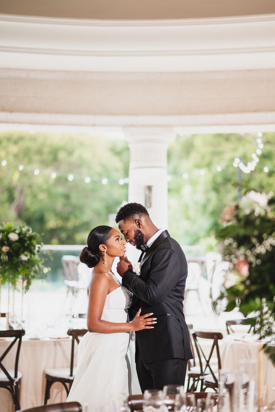 A romantic couple in formal wedding attire share a tender moment in a white dome reception venue at Sandy Lane barbados