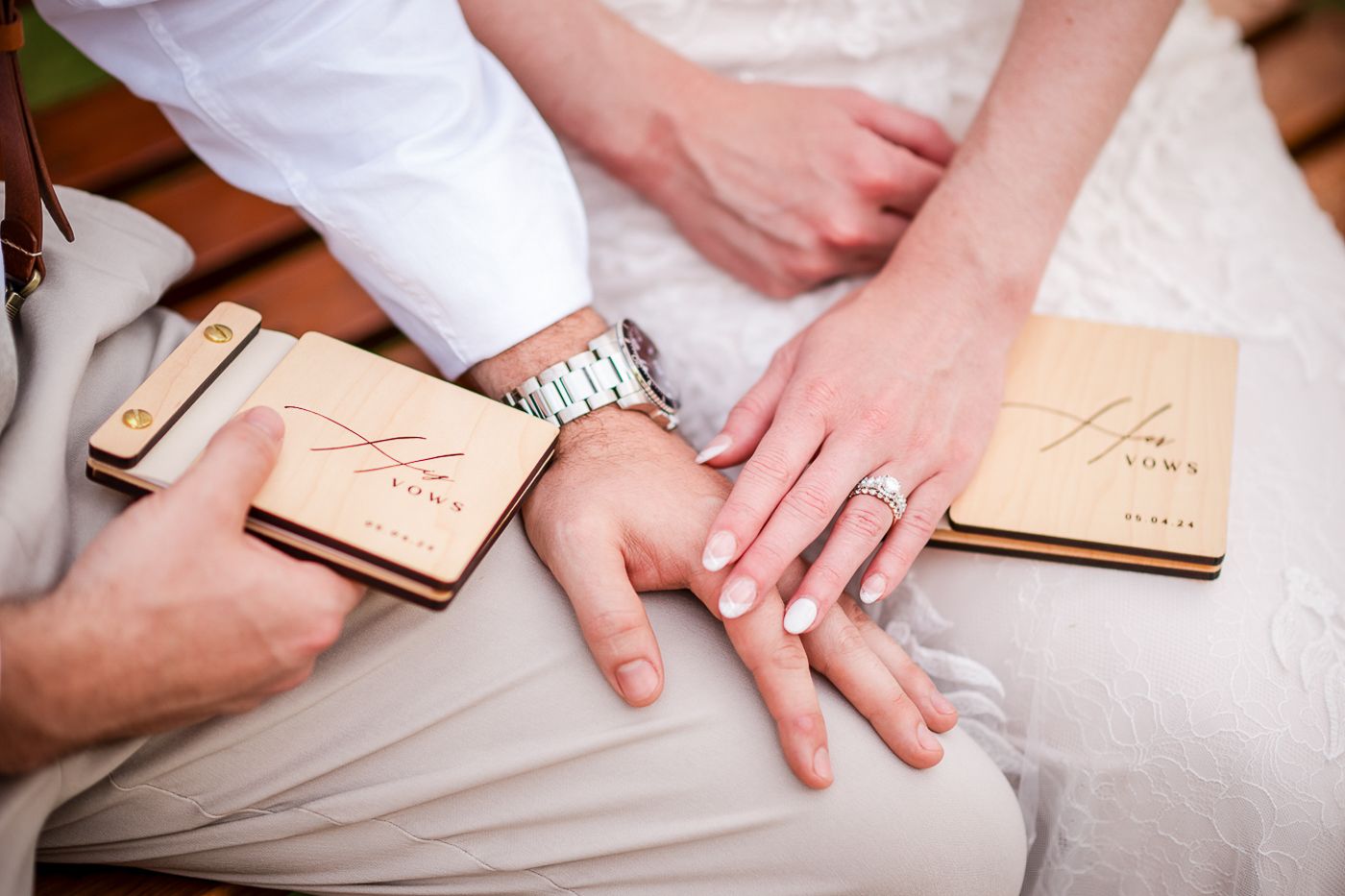 Close-up of hands touching together on a wooden surface with elegant details from a wedding ceremony.