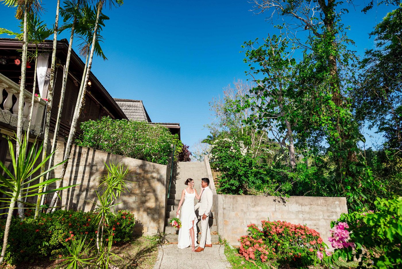Wedding venue exterior shots showing tropical architecture and landscaping under bright blue skies.