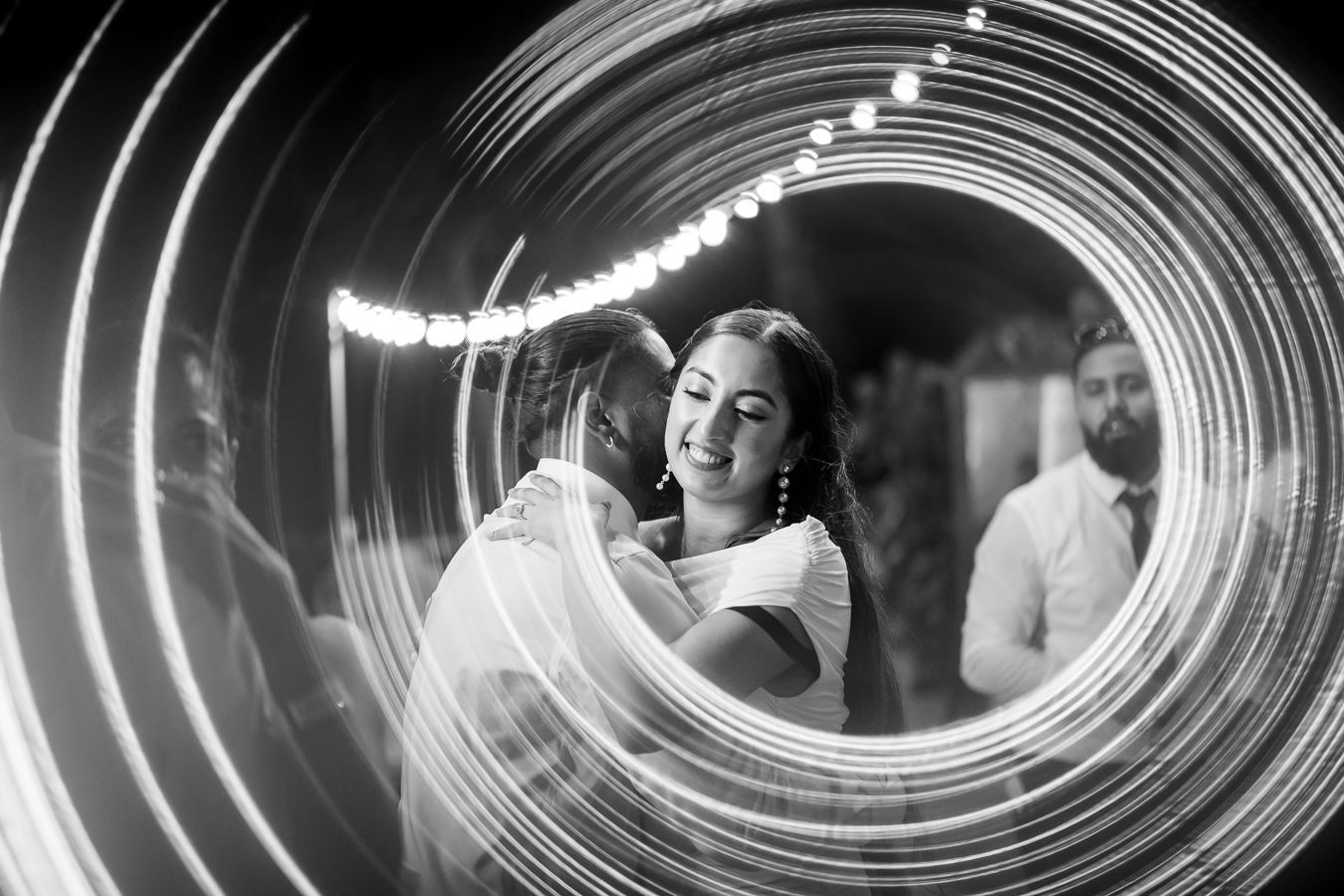Artistic black and white photo with spiral light trails creating dreamy wedding portrait.