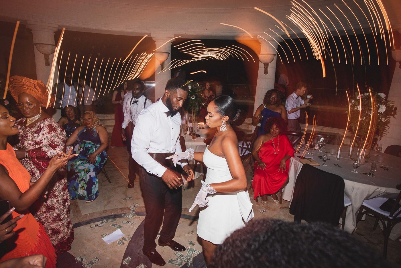 Energetic dance party scene at an indoor wedding reception with dramatic lighting.