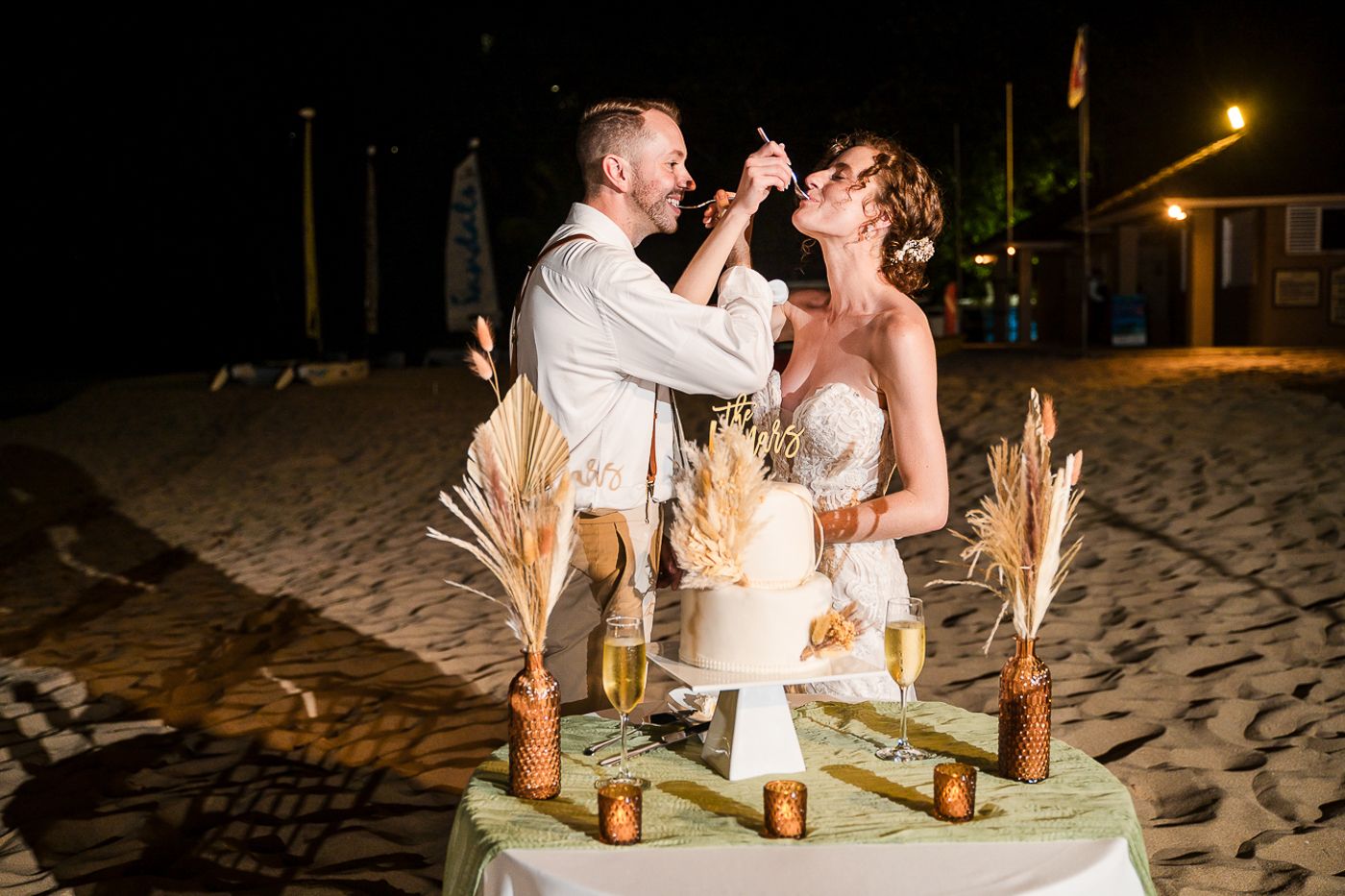 Romantic candlelit sweetheart table set on the beach at night.