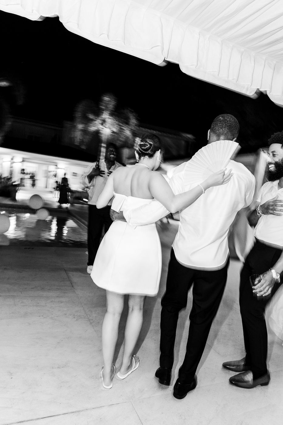 Black and white photo showing guests dancing in a line at a wedding reception.