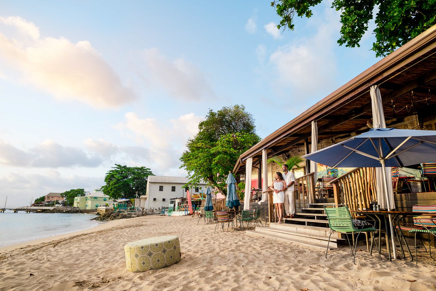 Beautiful barbados beachfront view with palm trees, wooden structures, and sandy shores.