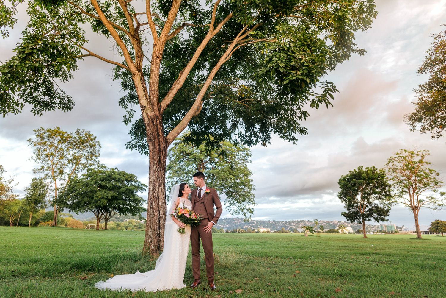 Wedding couple shares romantic moment under tall eucalyptus trees during golden hour.
