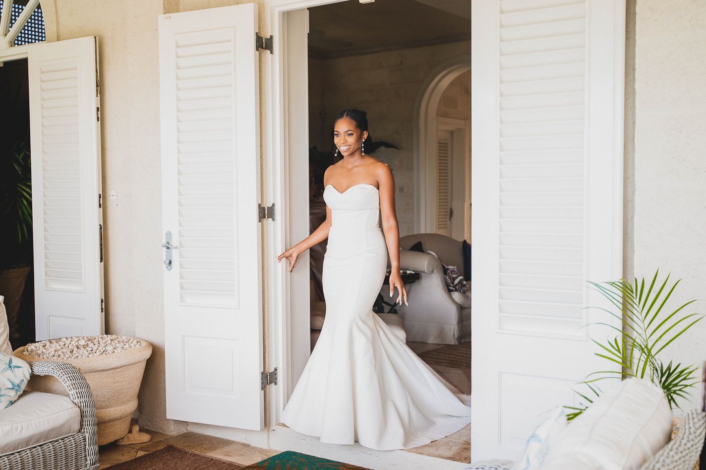 Bridal portrait in a fitted mermaid wedding gown standing in a doorway.