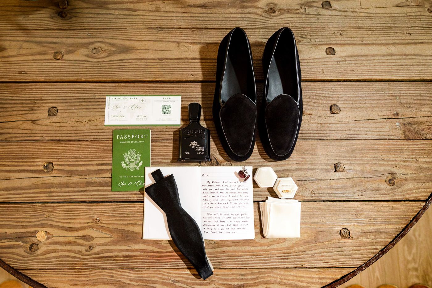 Groom's accessories including black loafers, socks and passport arranged on wooden floor.