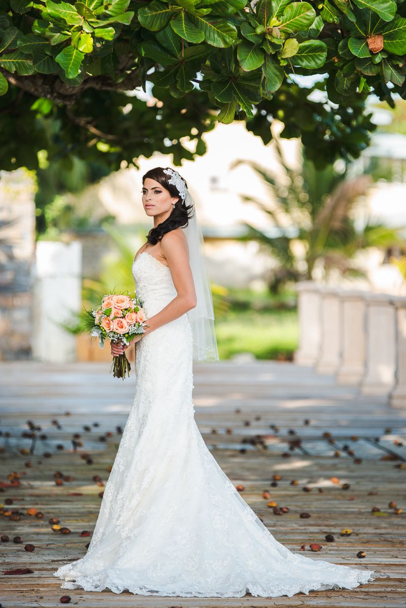 Beautiful lace wedding dress captured in outdoor garden setting with natural greenery.