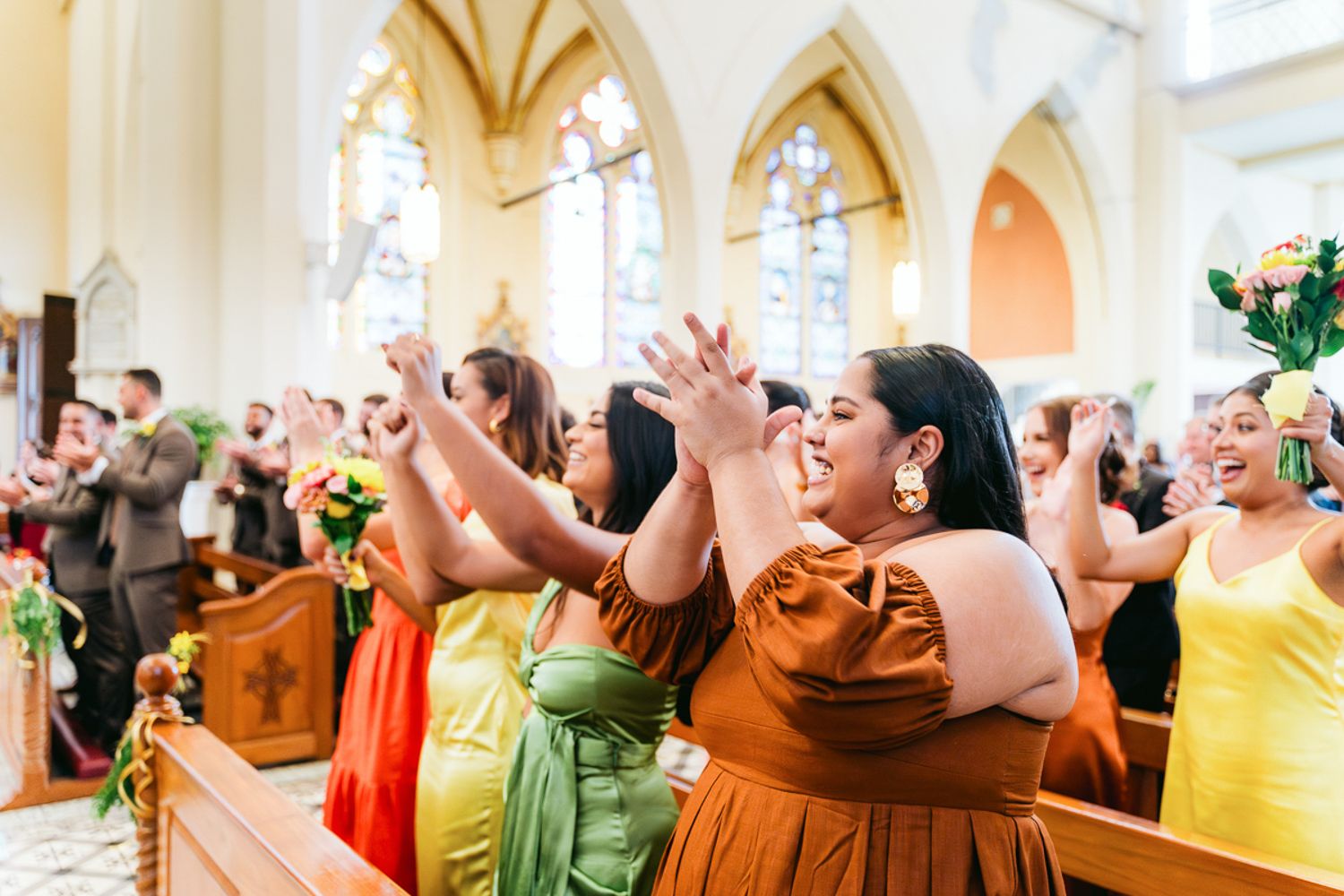 A large group of wedding guests perform a coordinated dance move during a reception celebration.